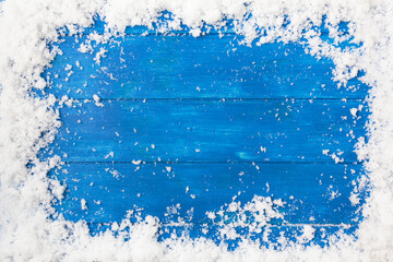 Top view of snow frame on blue wooden table with copy space. Winter or Christmas background