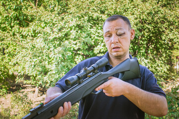 A man learns to shoot a gun. A man with a damaged eye holds a rifle in his hands. The guy tries to...