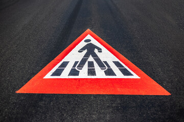 Close-up of pedestrian sign painted on asphalting road.