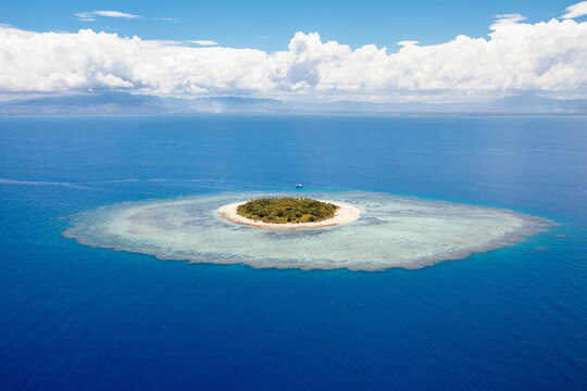 Perfectly round Mala Mala island in Fiji with white clouds on the horizon