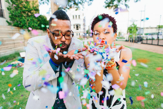 Hipsters blowing colorful confetti
