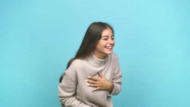 Young caucasian woman laughs happily and has fun keeping hands on stomach
