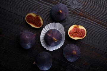 tasty ripe purple  figs with cutting  halfs  on black wooden table. close up. flat lay