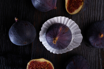 tasty ripe purple  figs with cutting  halfs  on black wooden table. close up. flat lay
