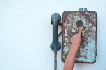 an old and rusty telephone hangs on the wall, the child is reaching out.

