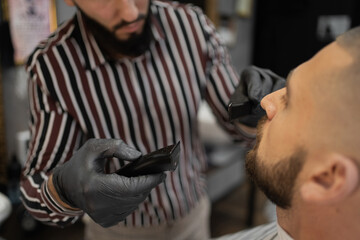 Obraz premium barbershop stylish haircut hairstyle short hair. a professional master Barber does his job, cuts the beard and hair of a friend's client with special tools