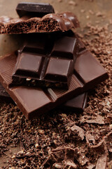 Composition of bars and pieces of different milk and dark chocolate, grated cocoa on a brown background top view close up