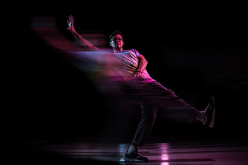 Professional break dancer jumping, practicing modern hip-hop dance in pink neon light, blur effect