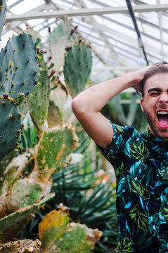 A young man wearing a tropical shirt making a funny face