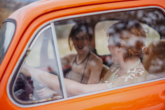 Tho girl friends enjoying the ride in an vintage car