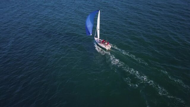 Aerial view of small sailboat flying blue spinnaker