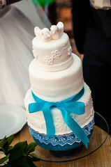 Three level wedding cake with two birds on top and blue stripe adound.