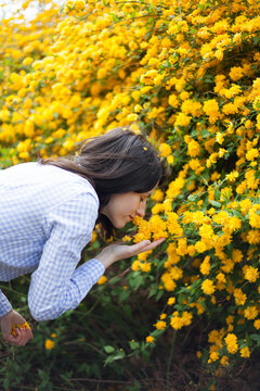 Young woman smelling yellow spring flowers outdoors