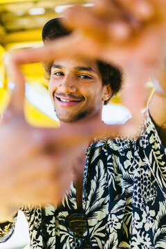 Man looking at camera through hands in frame shape.