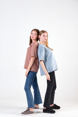 Pair of fashionable models posing in studio in brown and blue casual t-shirts for clothing catalog. Examples of autumn female fashion. Copy space. Concept of internet shopping and online sales.