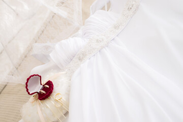 Wedding rings on the lace pillow and white wedding dress.