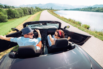 Couple in love getting into the convertable auto and starting a trip. Couple honeymoon or vacation...