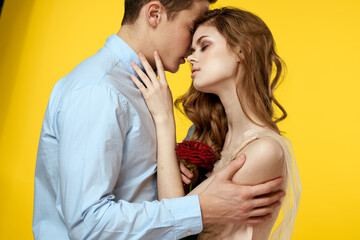 Enamored man and woman with red rose on yellow background cropped view close-up romance