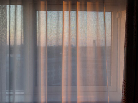 Curtains on a window catching light from the setting sun