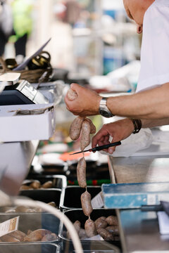 Man cutting linked sausages on butcher's market stall