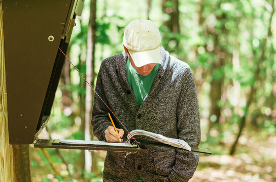man signing name in a register at a trailhead