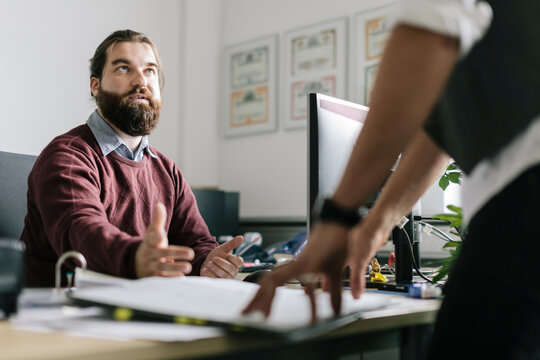 Serious manager asking questions over documents to businessman