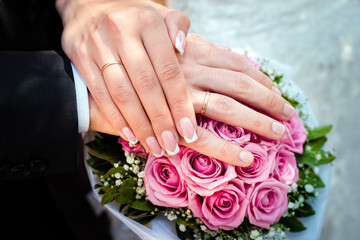 Obraz na płótnie Canvas Close up picture of the bride's and groom's hands with wedding rings on a bridal bouquet 