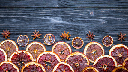 Dried citrus fruits composition with orange, lime, lemon, grapefruit, anise. Dark natural wooden background. Autumn season layout. Flat lay, top view, copy space. 