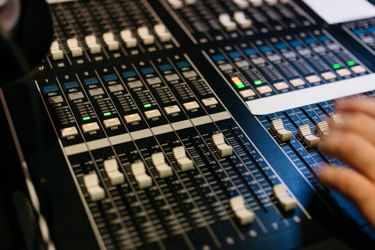 Sound engineer's hands on mixer board faders