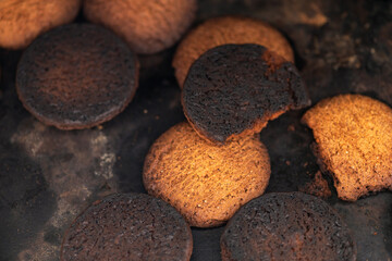 Burnt cookies. Burnt, burnt oatmeal cookies lie on a black baking sheet.