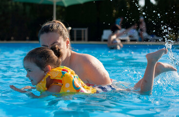 Mom teaches her little daughter to swim. The coach teaches a girl to swim in the pool. Rest in warm countries. Rest at the hotel