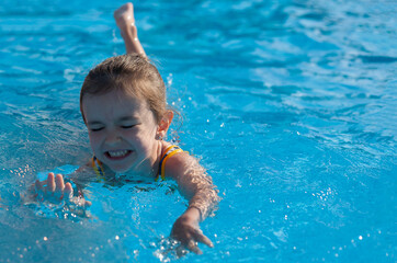 Fototapeta na wymiar Little girl swims in the pool