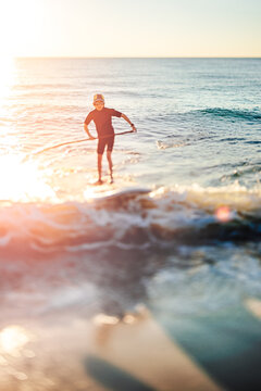 Boy riding a wave on a stand up paddle board at sunset