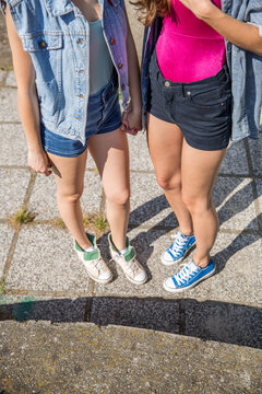 Legs of two young teenage girls standing on hot summer asphalt