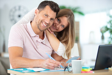 positive young couple calculating the bills at home