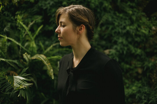 Woman in black shirt in greenhouse with natural light on her face from above