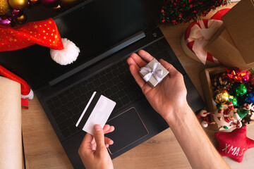 Man shopping online with laptop at christmas at home in holiday decor