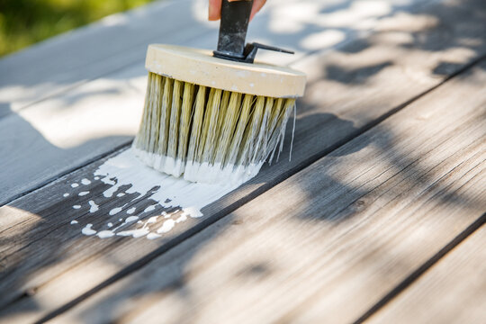 Wide painter's brush applying the first coat of white paint
