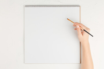 notebook with empty sheet with pencil in hands