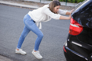woman pushing a broken down car