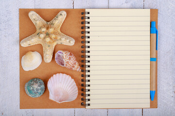 Notebook for writing your vacation memories. A blank sheet and seashells from the seaside.