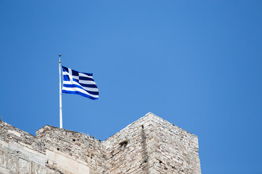 The Greek Flag on the Acropolis as Seen from Below with a Clear Blue Sky