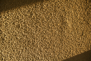 Grainy background, yellow wall surface texture shot on a sunny day, hard shadows