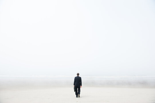 Businessman walking on a foggy beach