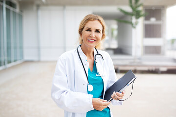 &Auml;rztin mit Kittel und Stethoskop vor einem Krankenhaus 