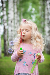 little girl with curly blonde hair on a walk, summer day