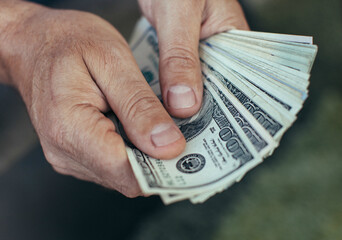 Man counting a large stack of hundred dollar bills