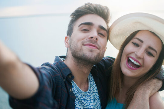 A young couple smiling and laughing while taking a picture on vacation