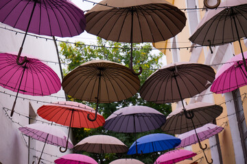Fototapeta na wymiar Background of city street decoration of colorful umbrellas.Colorful umbrellas hanging out above the old streets beetween old buildings.