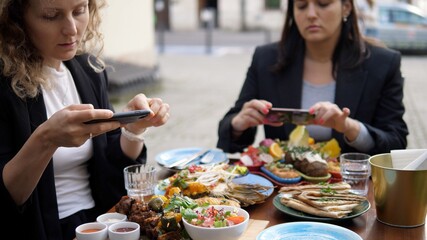 Two young women taking pictures of their healthy vegan lunch. Work of a Food blogger 